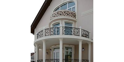 Балкон второго этажа поддерживают колонны с декором из полиуретана